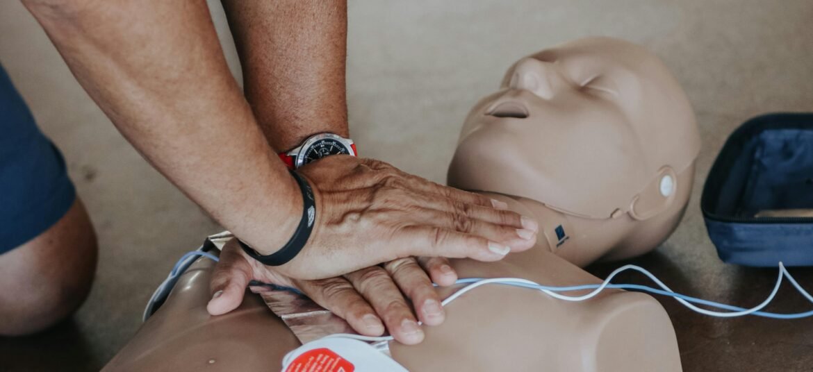 Hands performing CPR on a medical training manikin during a first aid course