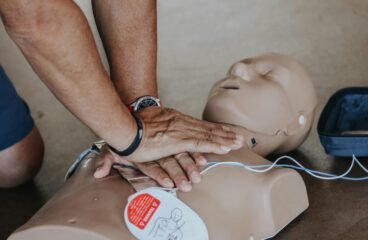 Hands performing CPR on a medical training manikin during a first aid course