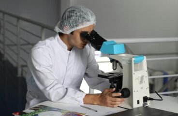 healthcare sector – lab technician analyzing samples under microscope