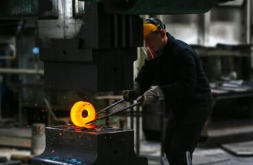 industry sector – worker handling hot metal in manufacturing plant