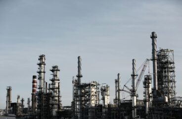 oil and gas sector – industrial refinery towers under blue sky
